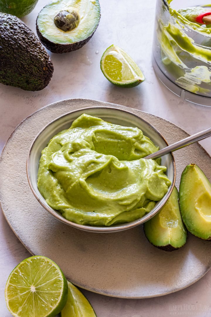 Vegan and dairy-free avocado mayonnaise with fresh avocados and limes on the table.