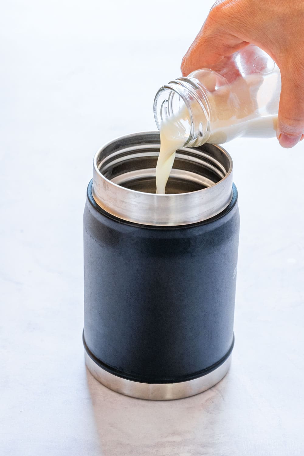 Pouring oat milk to Stanley thermos.