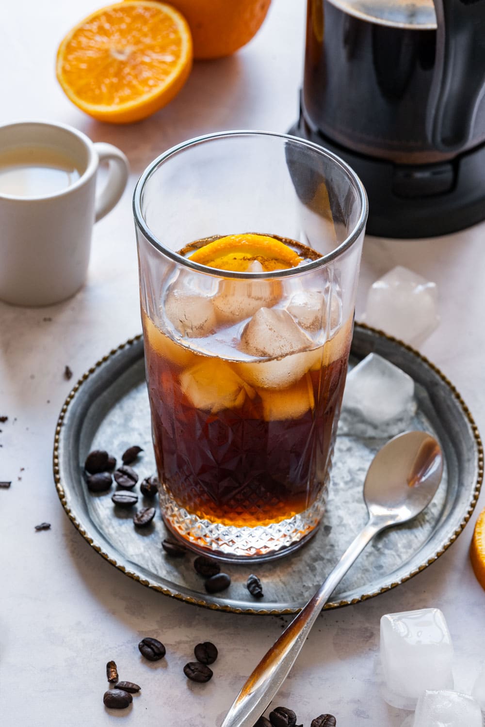 Glass of orange cold brew coffee with ice and orange slice.