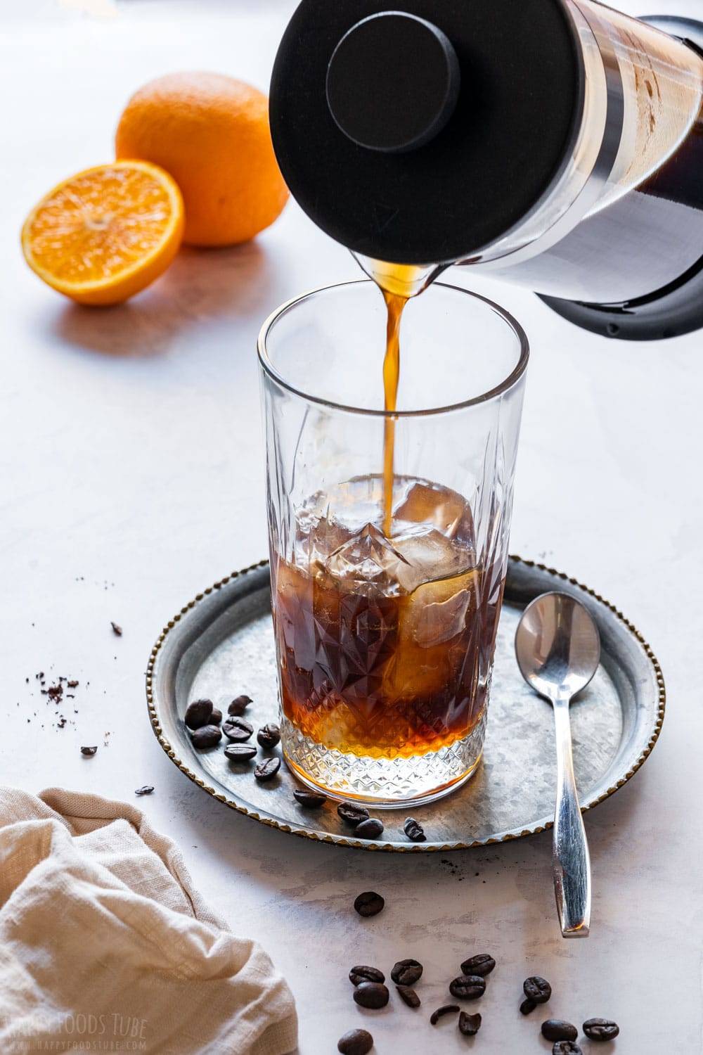 Pouring orange cold brew to glass filled with ice.