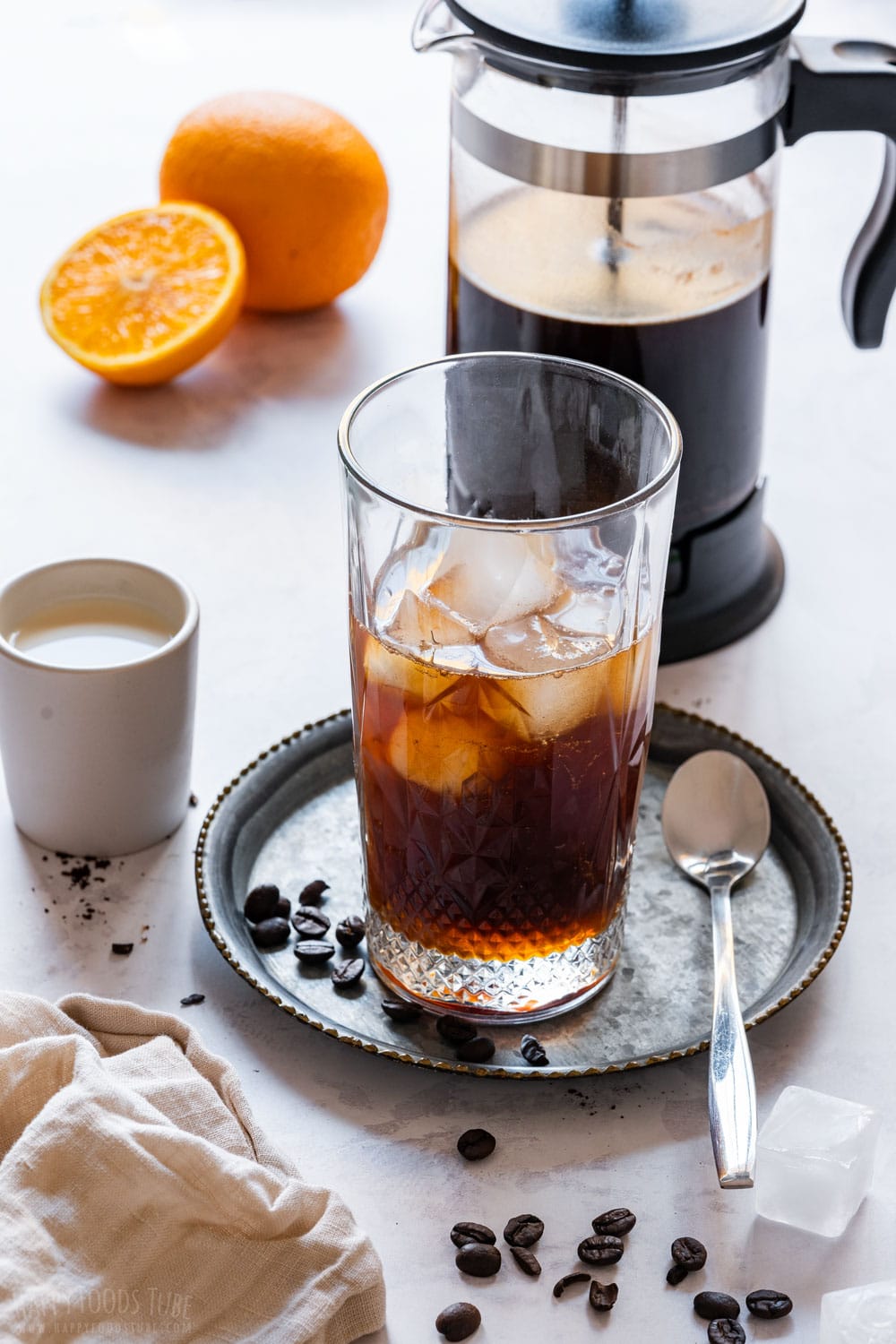 French press and glass of orange cold brew with ice.