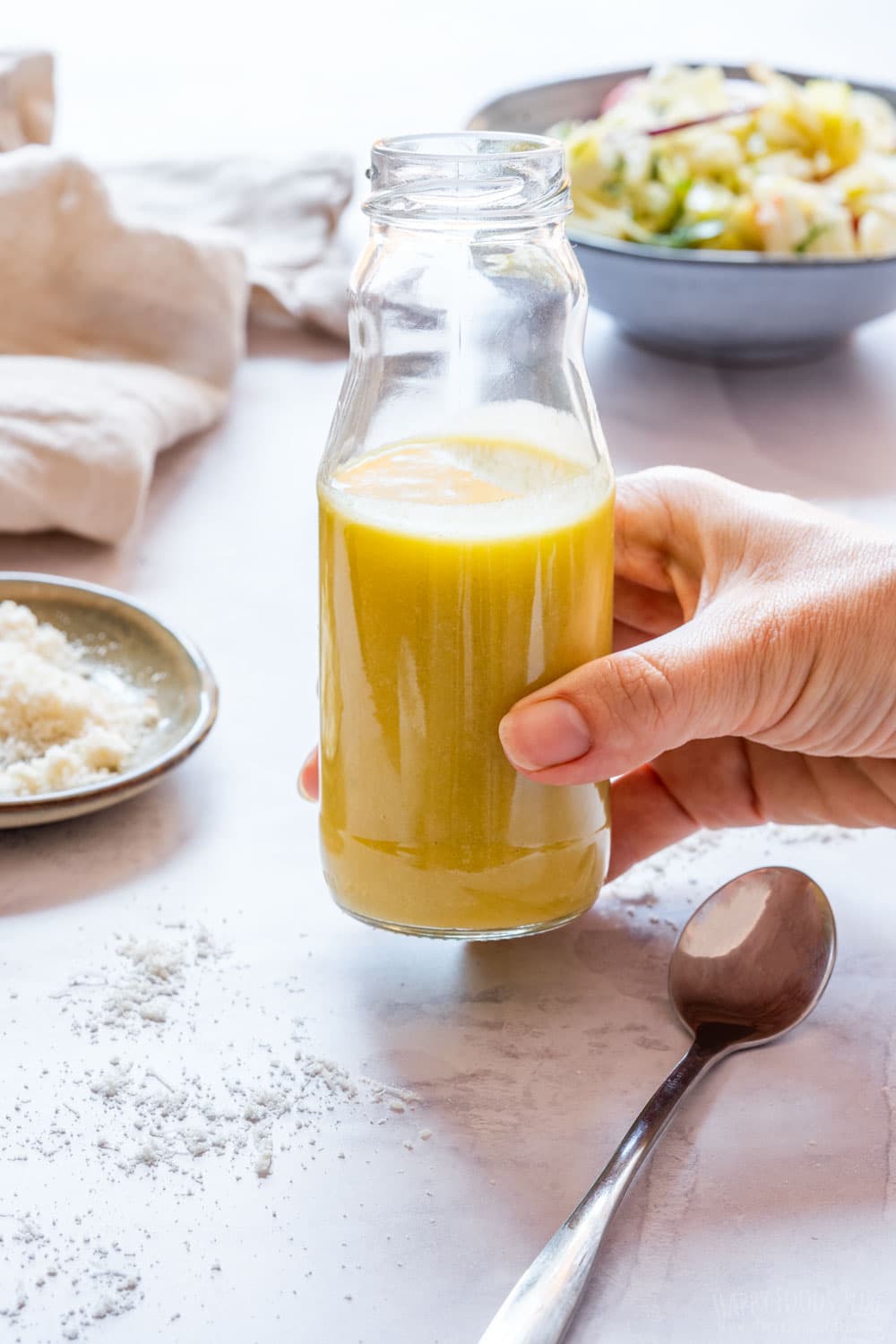 Holding bottle of freshly made parmesan vinaigrette.