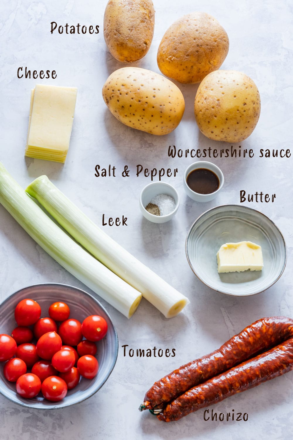 Ingredients of twice baked potatoes - potatoes, tomatoes, leek, chorizo, cheese, worcestershire sauce, salt and pepper.