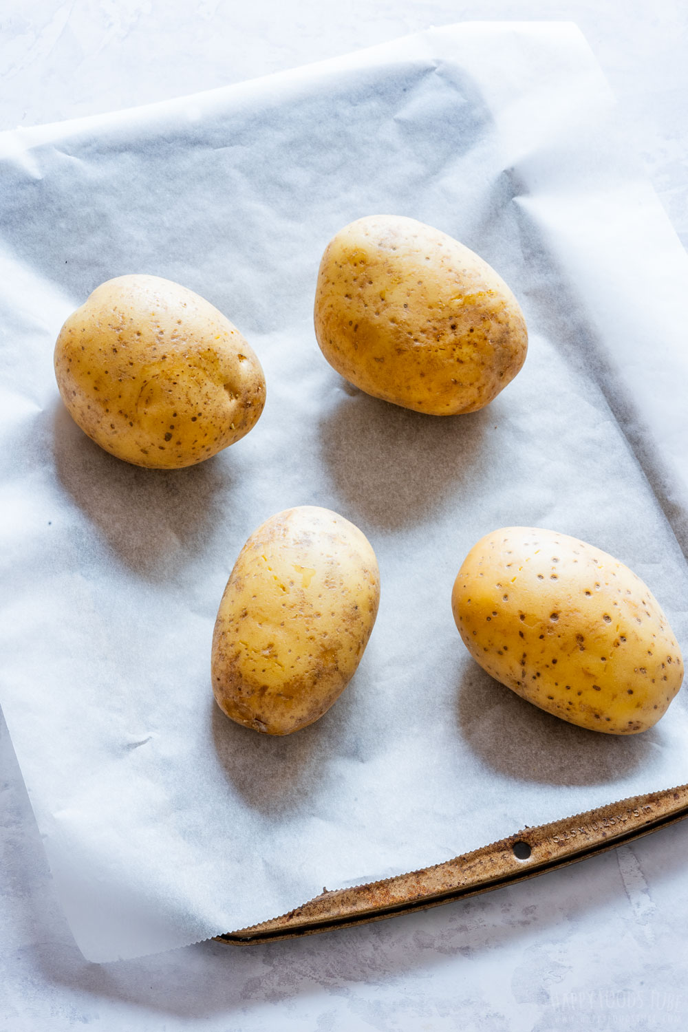 Four potatoes on the baking tray.