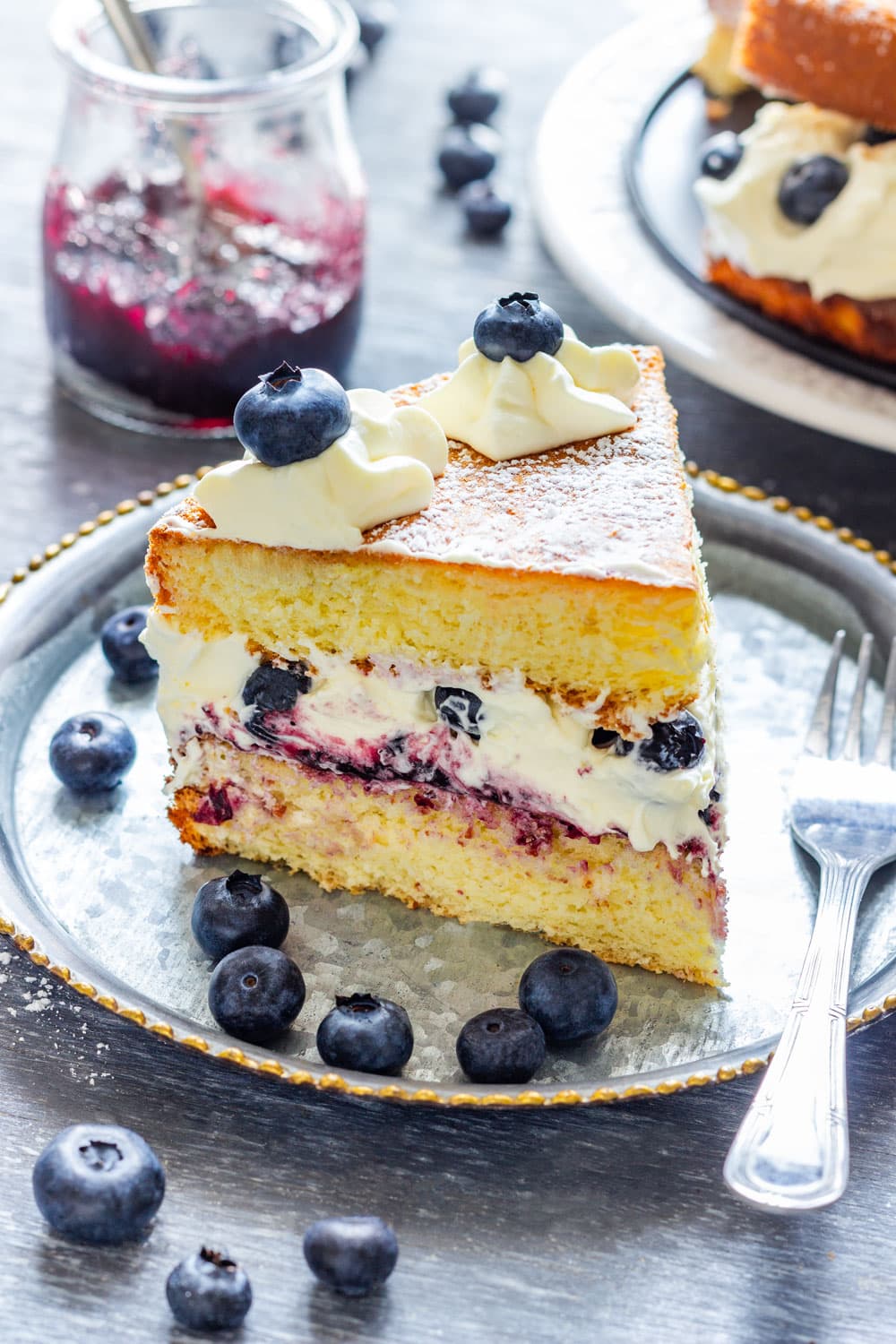 Slice of blueberry cream cake with fresh berries.