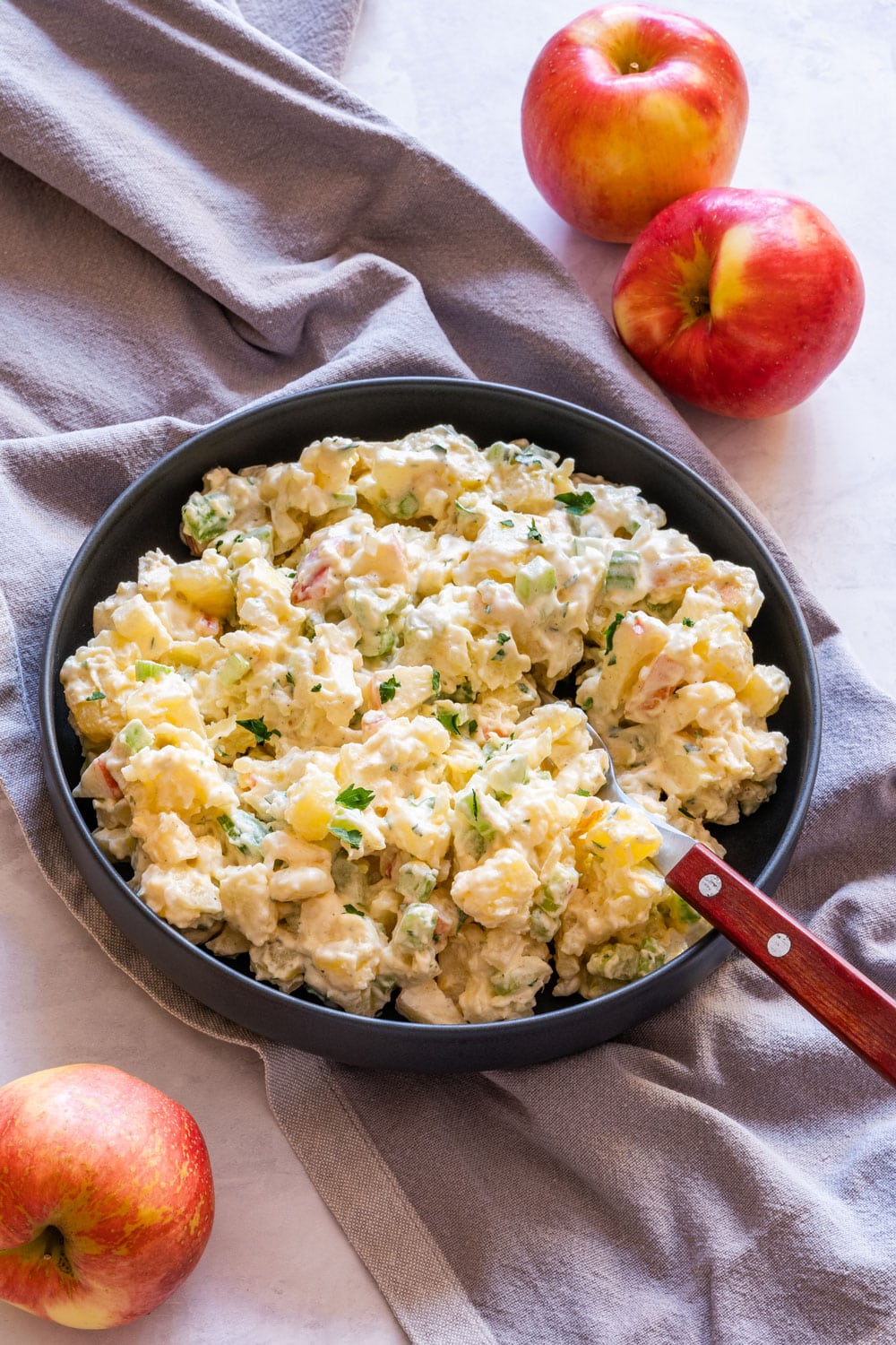 Homemade creamy potato salad with apples on the plate with fork.