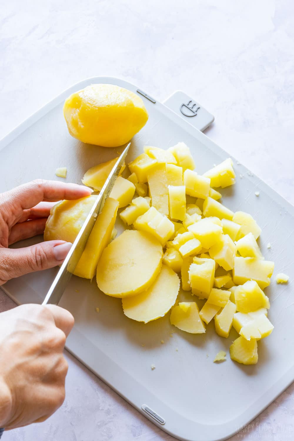 Cutting boiled potatoes on the chopping board.