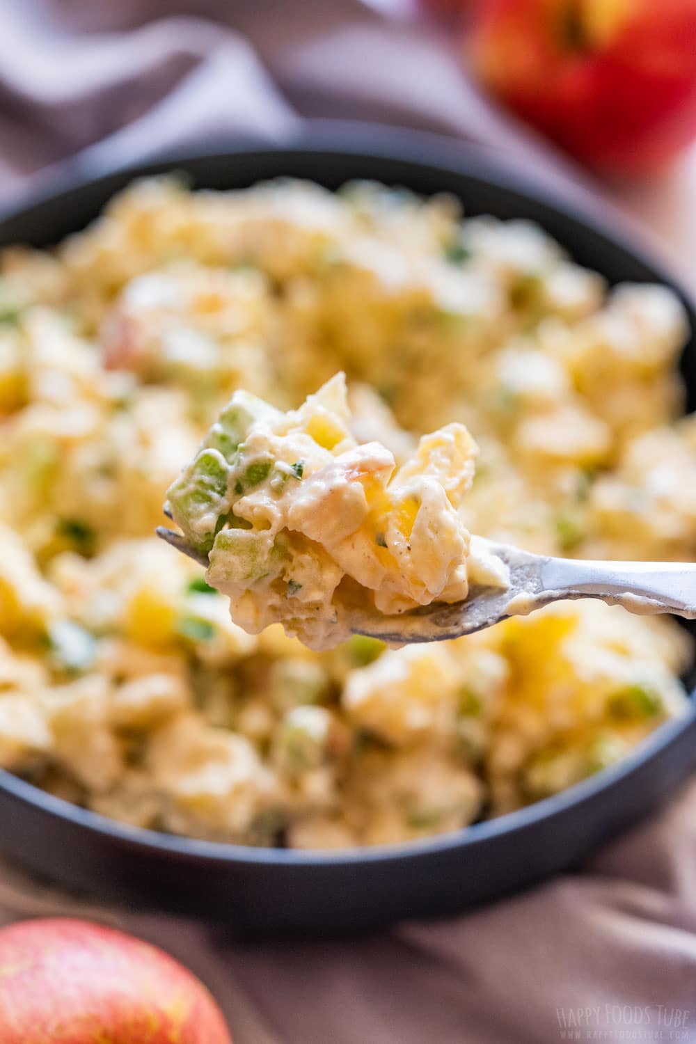 Forking potato salad with apples and celery.
