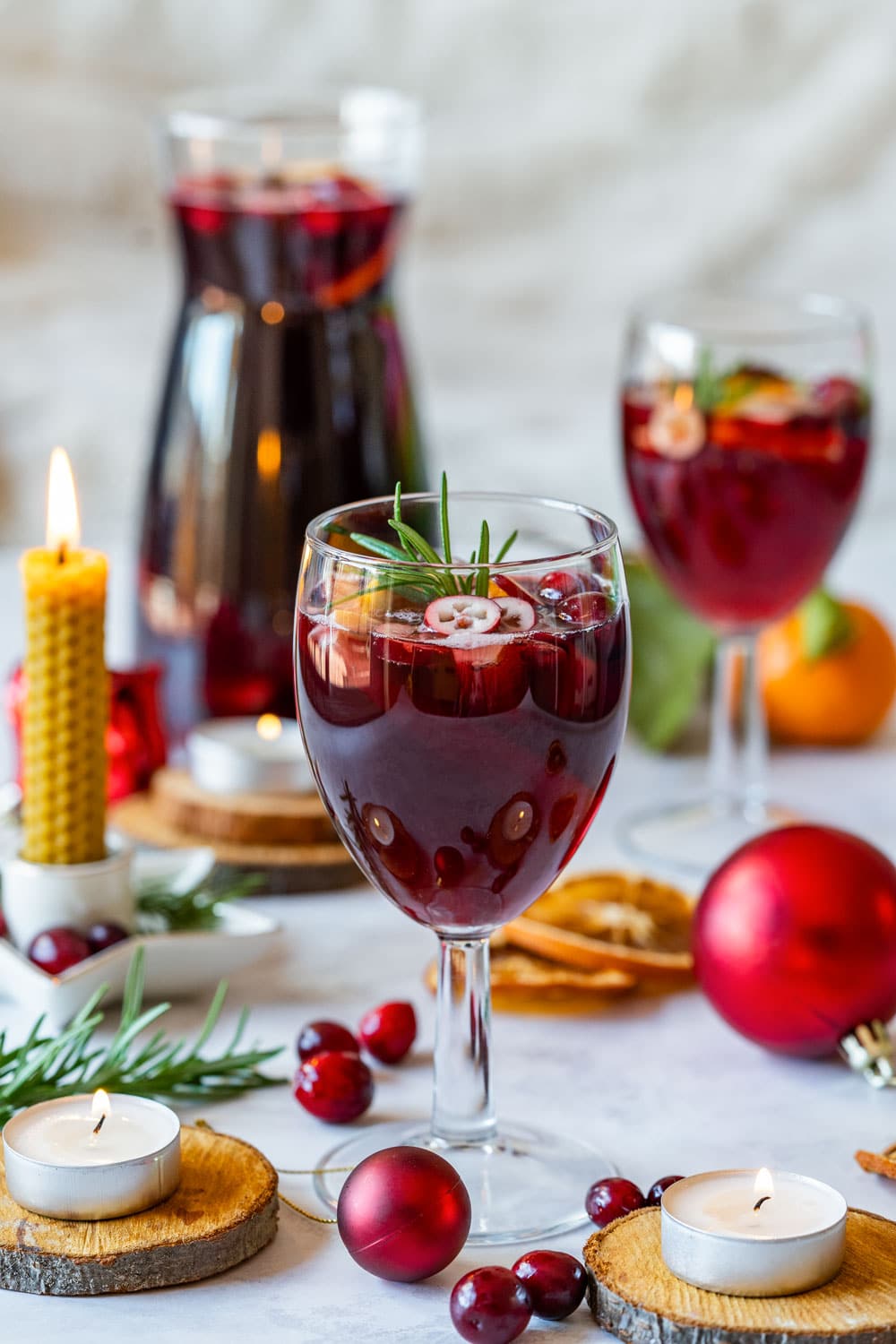 Glass of festive Christmas sangria surrounded with candles and holiday decorations.