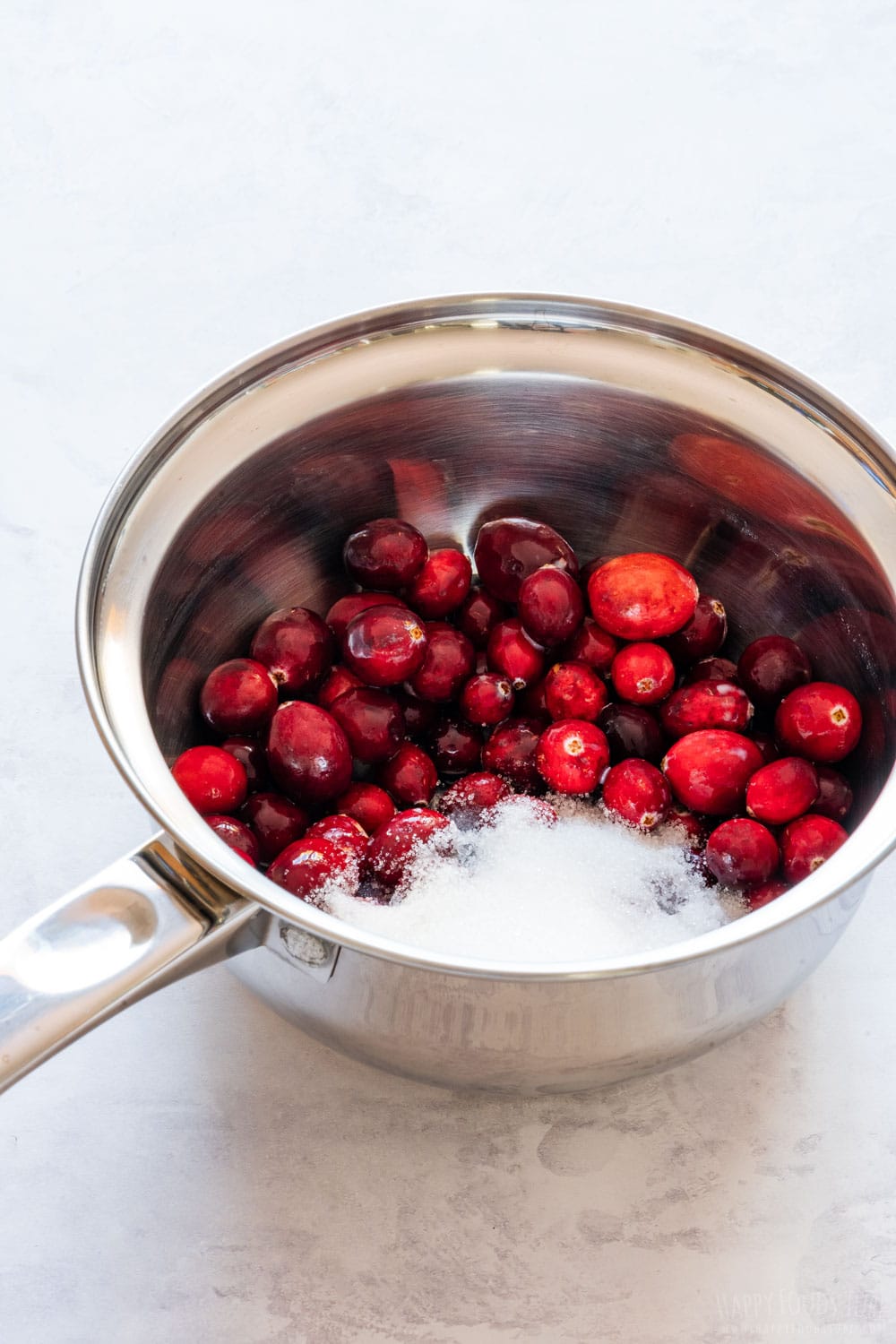 Fresh cranberries with sugar in the saucepan.