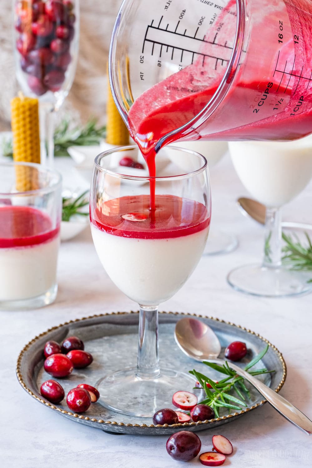 Pouring cranberry sauce over refrigerated panna cotta.