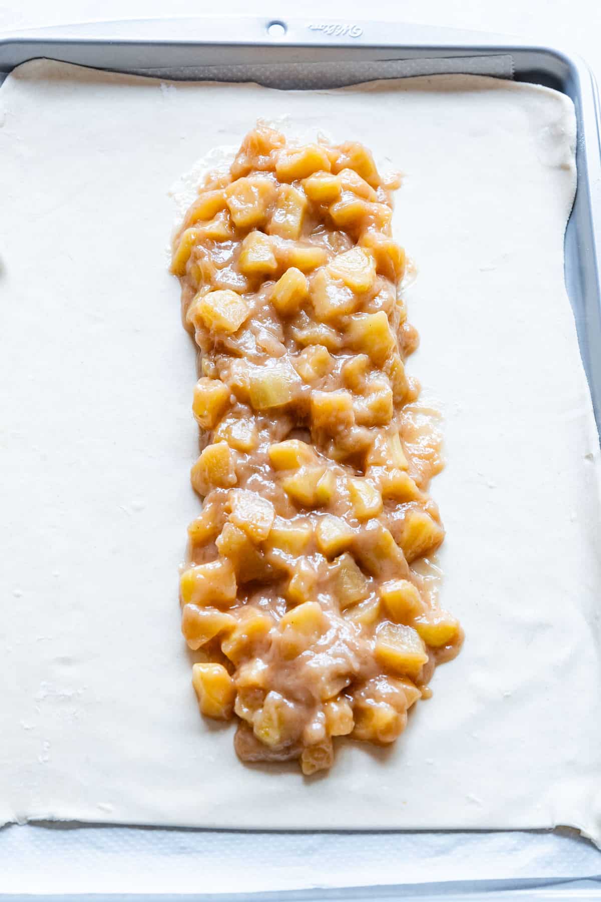 Filling puff pastry apple strudel.