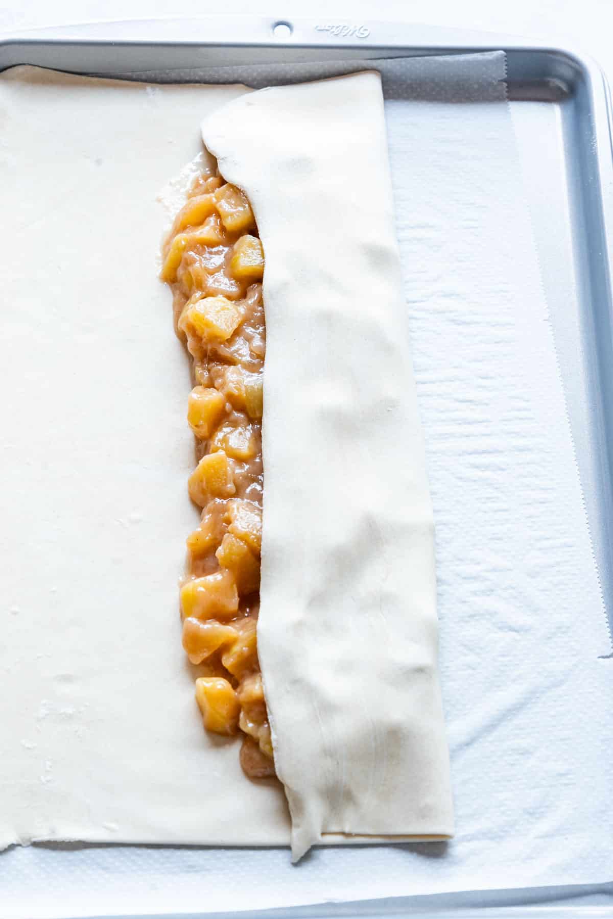 Folding puff pastry apple strudel.