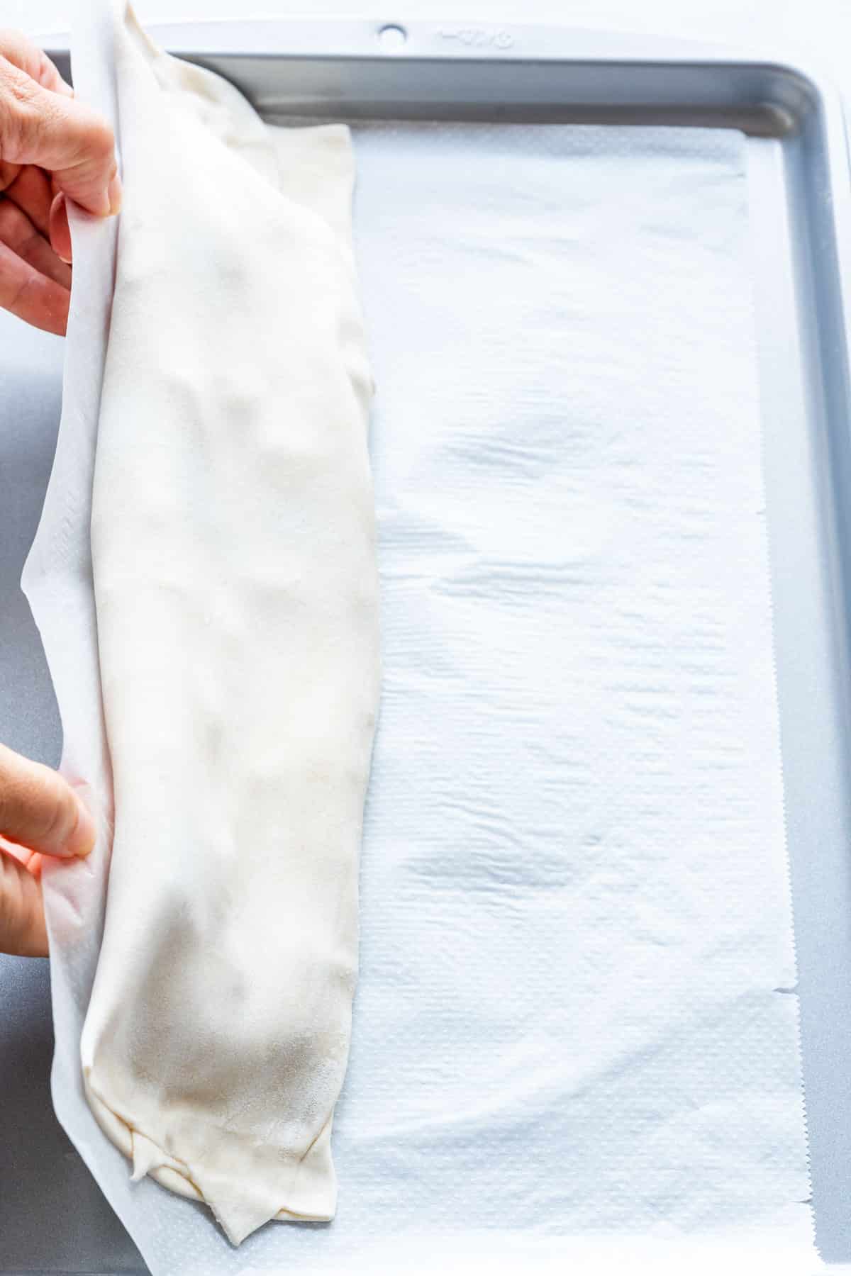 Rolling the strudel over so that the folded part is at the bottom.