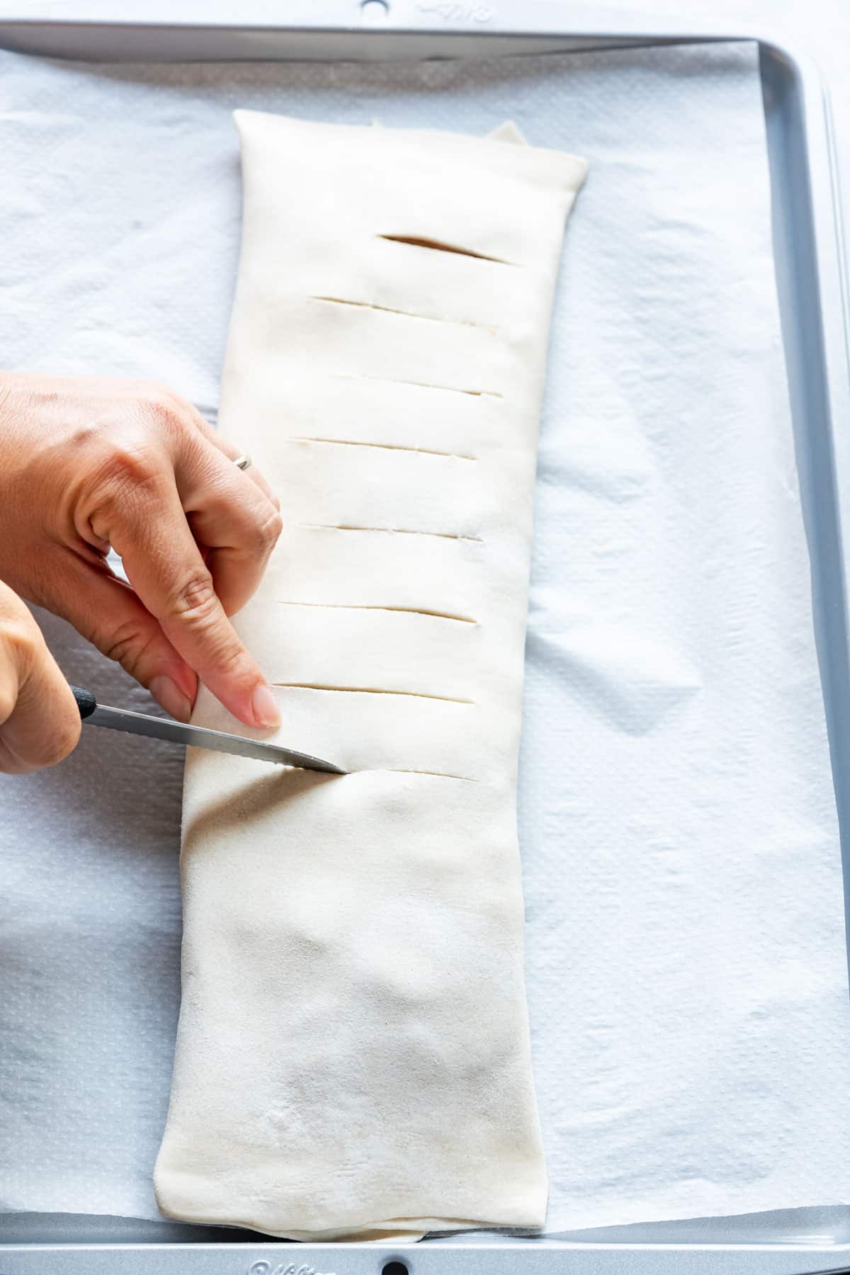 Scoring puff pastry apple strudel.