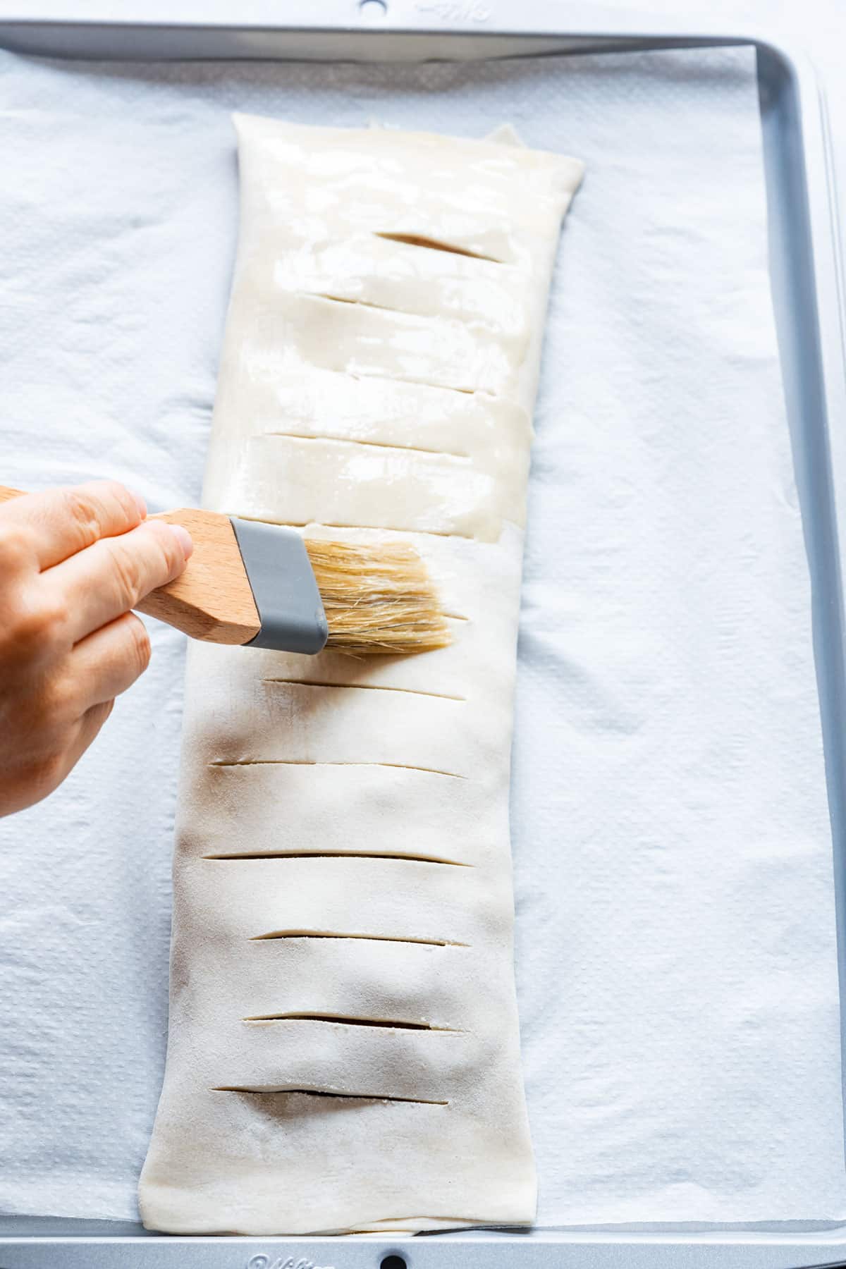 Brushing apple strudel with melted butter.