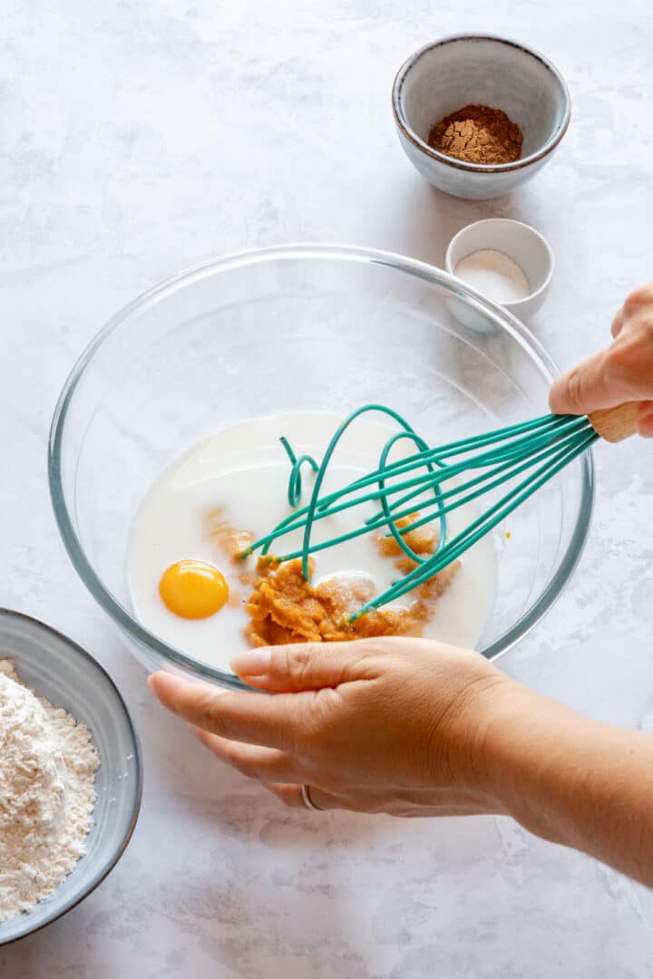 Whisking eggs, milk and pumpkin puree in a bowl.