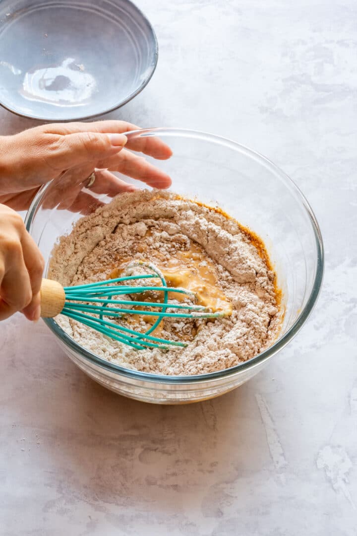 Whisking pumpkin pancake batter in a large glass bowl.