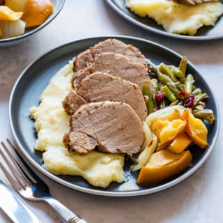 Comforting meal, sliced pork tenderloin with mashed potatoes, baked apples and onions.