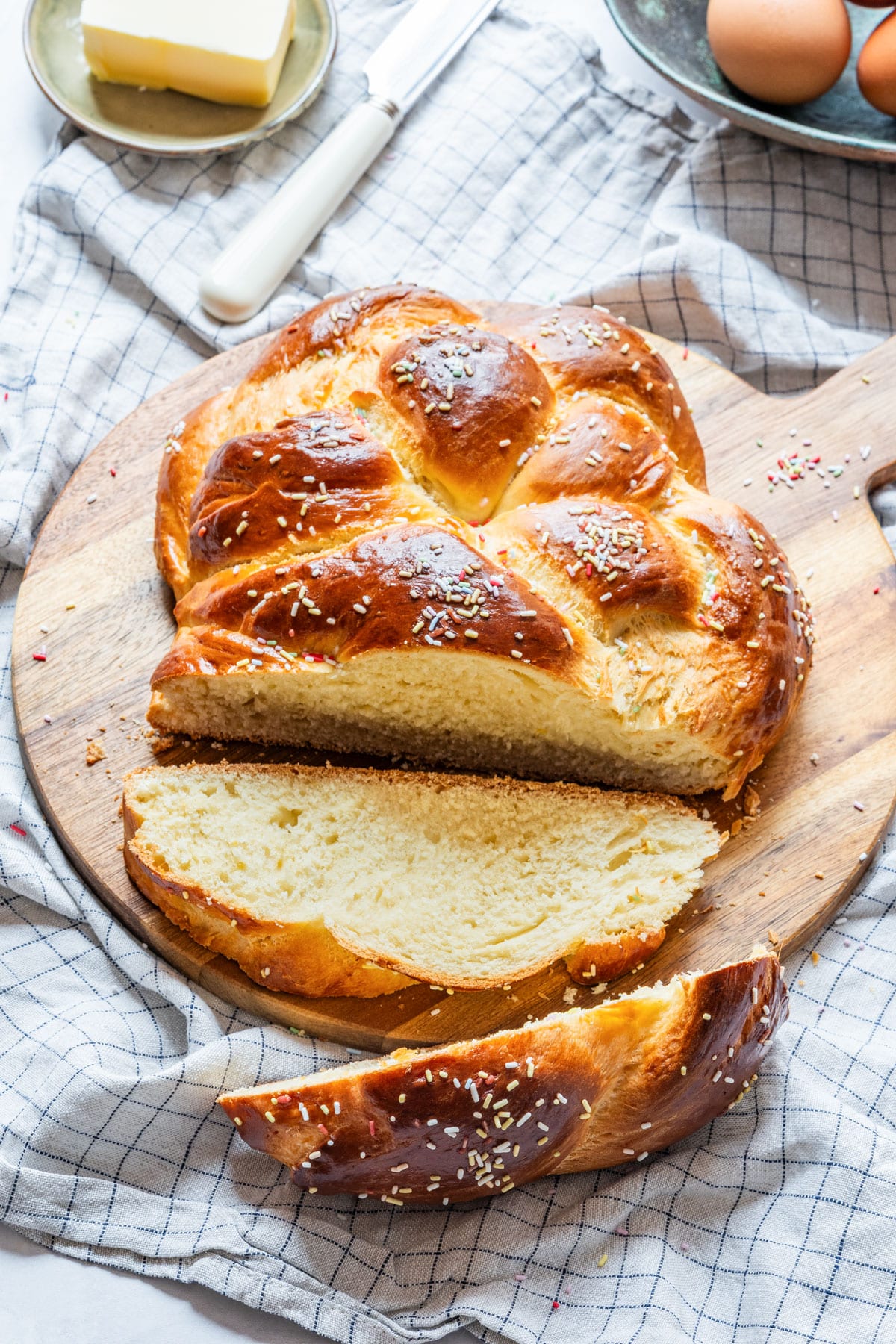 Freshly baked Easter bread with golden crust and sprinkles, sliced on a wooden board.
