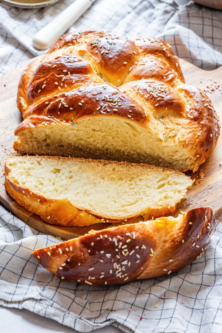 Close-up of sliced sweet Easter bread with shiny golden crust and colorful sprinkles.