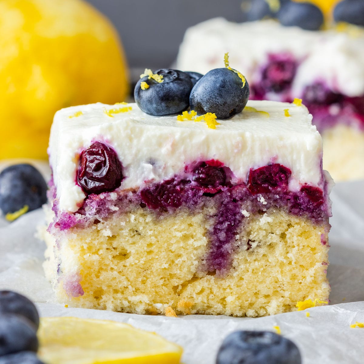 Slice of lemon blueberry cake topped with whipped frosting and fresh blueberries.