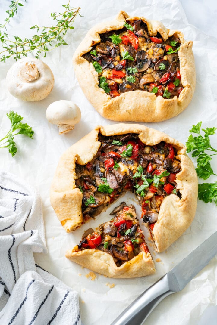 Two galettes filled with mushrooms, red peppers and herbs, with a slice cut out of one.