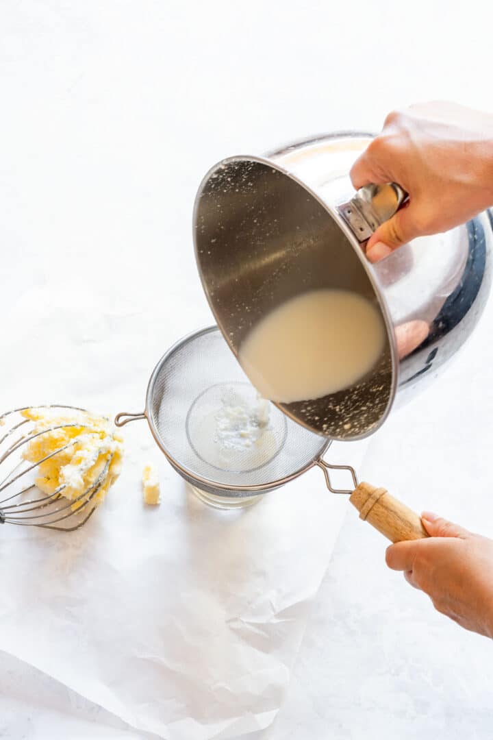 Separating buttermilk from butter solids using a strainer.
