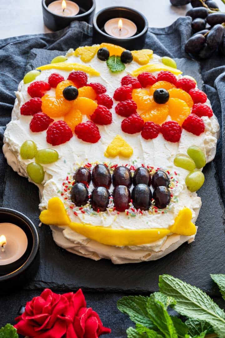 Day of the Dead (Dia de los Muertos) sugar skull dessert on a slate board with candles and roses.