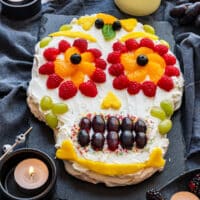Day of the Dead sugar skull pavlova on slate with candles, roses and mint.
