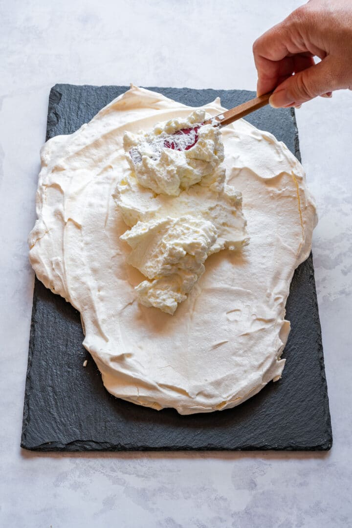 Spreading whipped cream over the baked meringue base.
