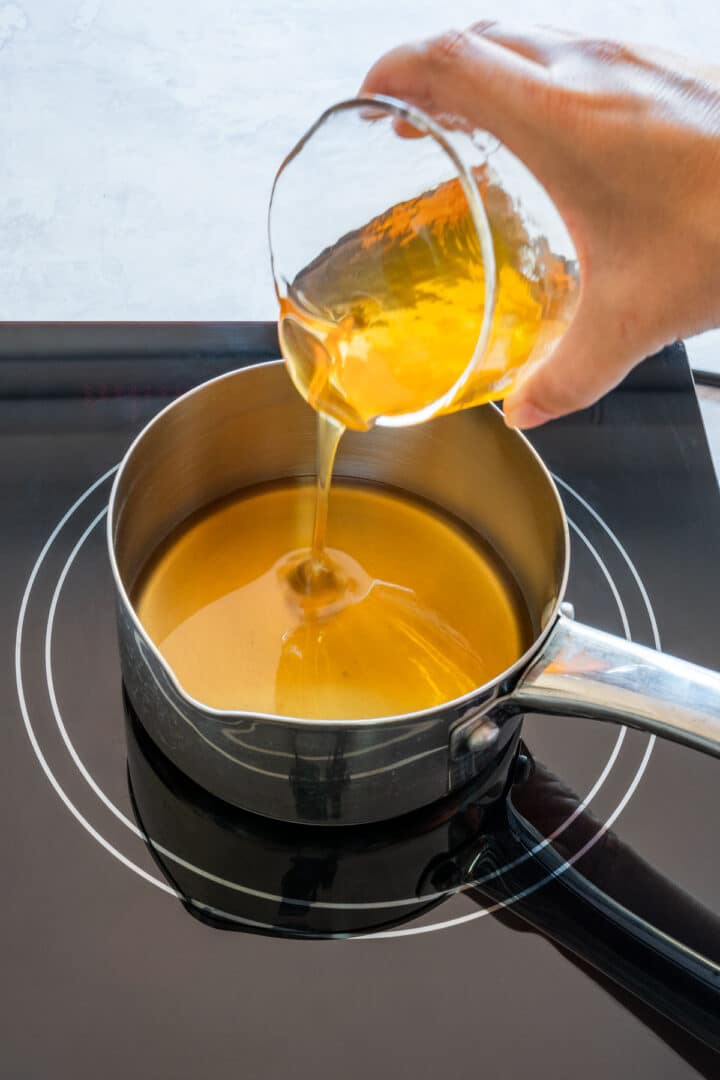Pouring honey into a saucepan to start making hot honey.