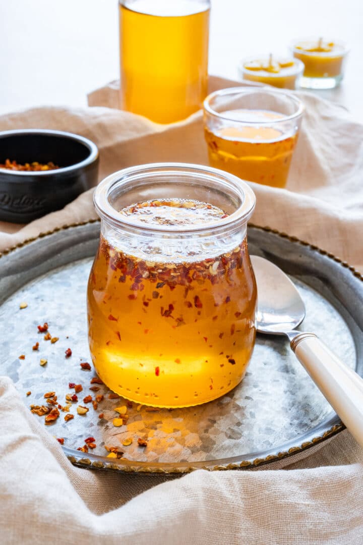 Jar of sweet and spicy hot honey cooling on a tray.