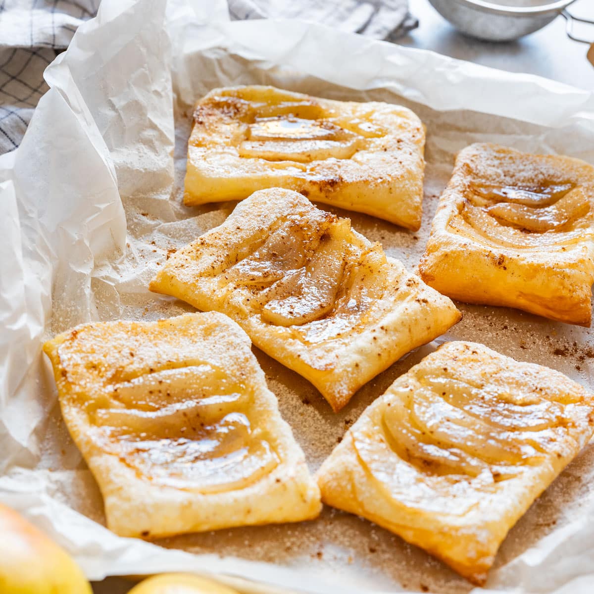 Golden baked pear tarts with flaky puff pastry and a light dusting of powdered sugar.