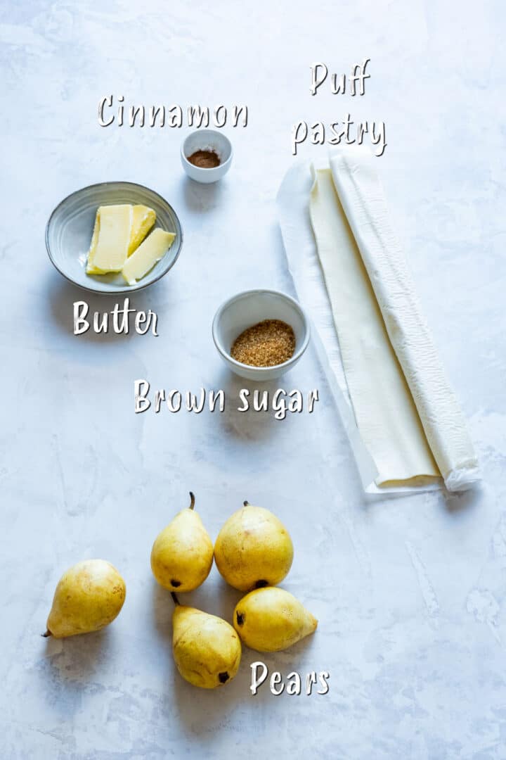 Ingredients for pear tarts including pears, puff pastry, butter, brown sugar and cinnamon.