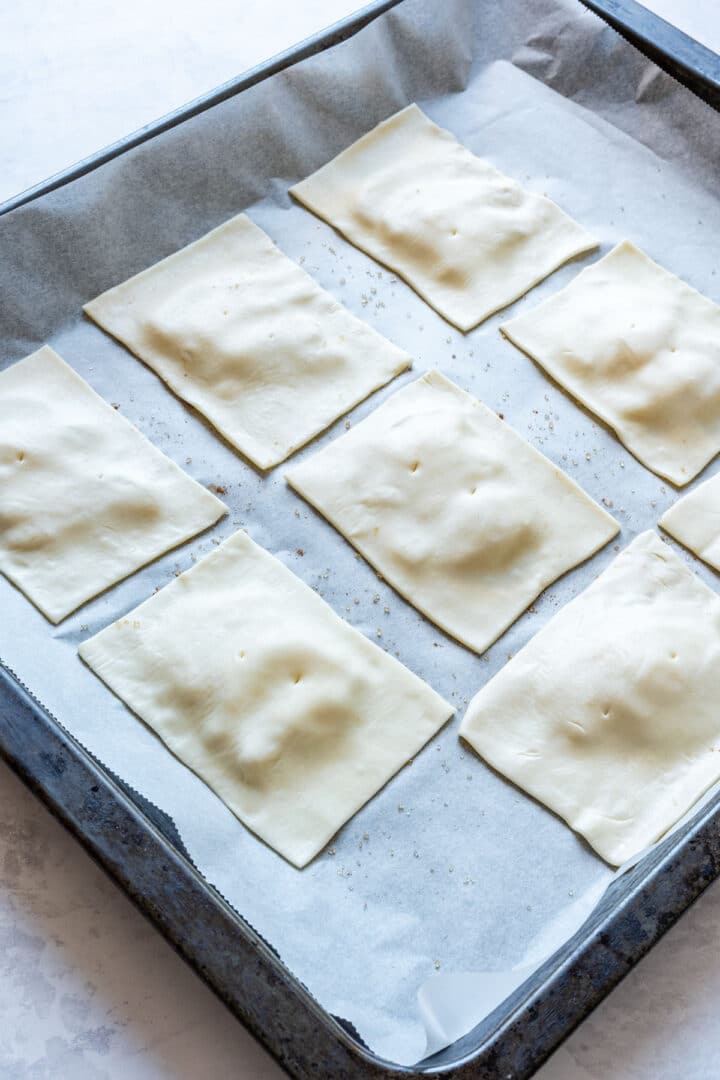 Prepared pear tarts on a baking sheet ready to bake.