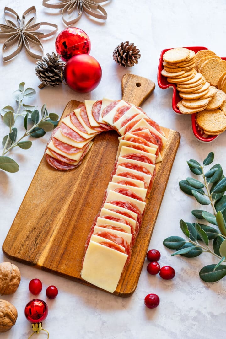 Overhead view of full candy cane salami and cheese board with festive decor and crackers.