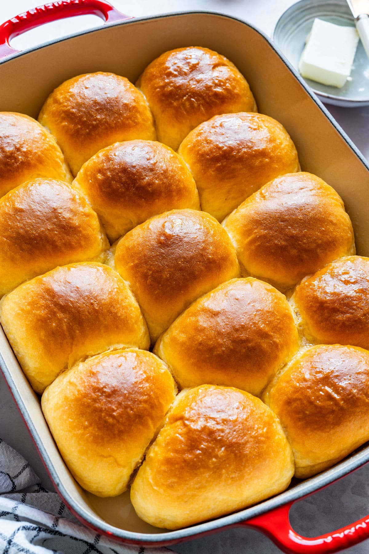 Golden sweet potato dinner rolls in a red baking dish, just baked.