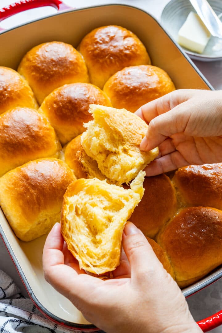 Pulling apart a warm roll to show the soft, fluffy interior.