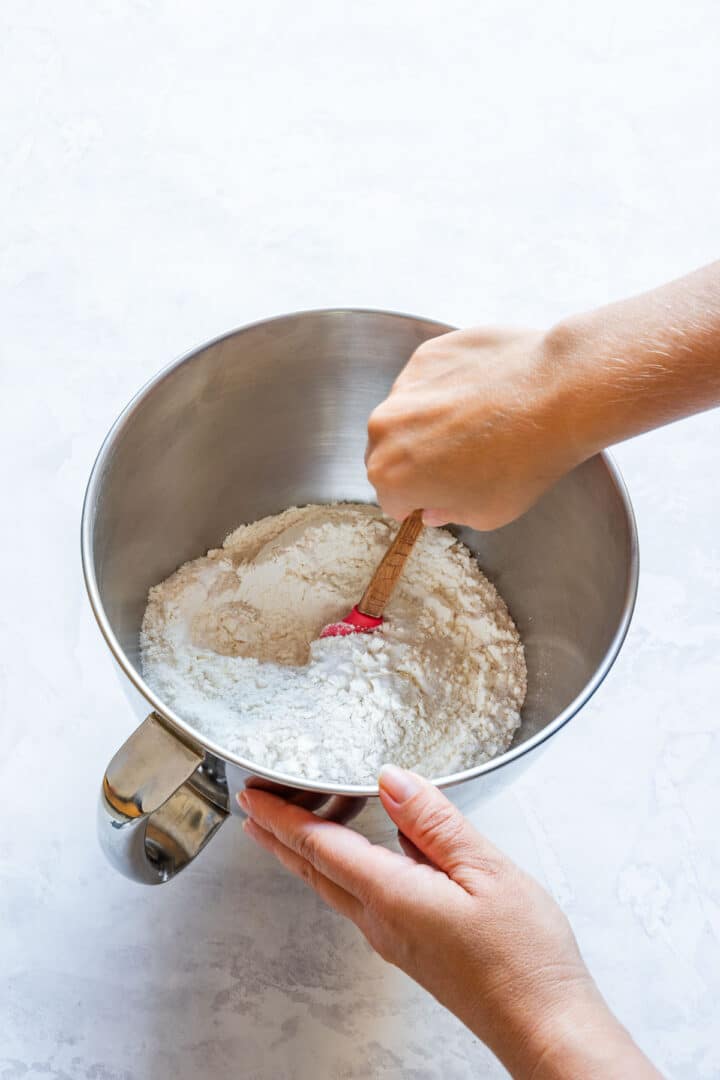 Stirring flour, yeast, sugar and salt together in a stand mixer bowl.