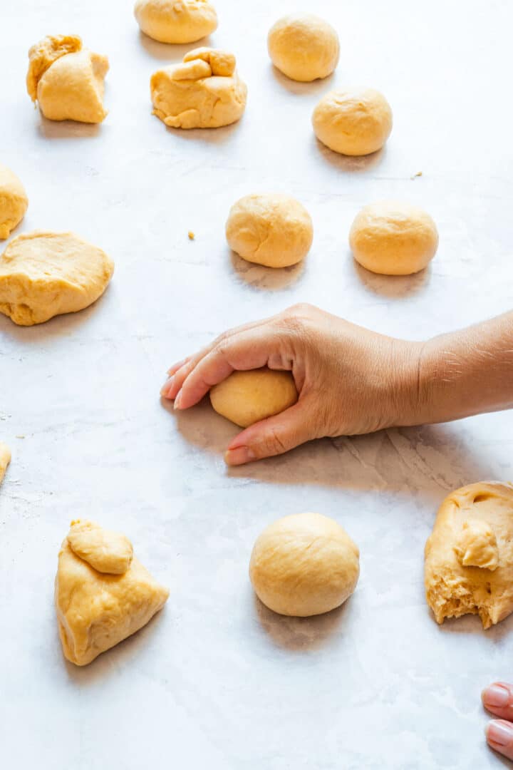 Shaping pieces of dough into small balls on a lightly floured work surface.