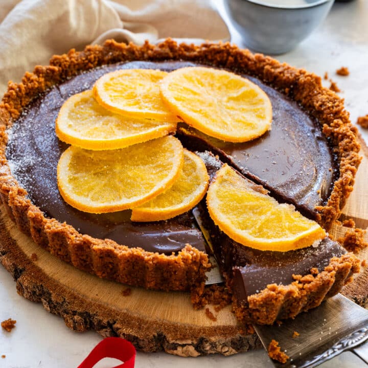 Lifted slice of chocolate orange tart showing thick ganache filling and crumb crust.