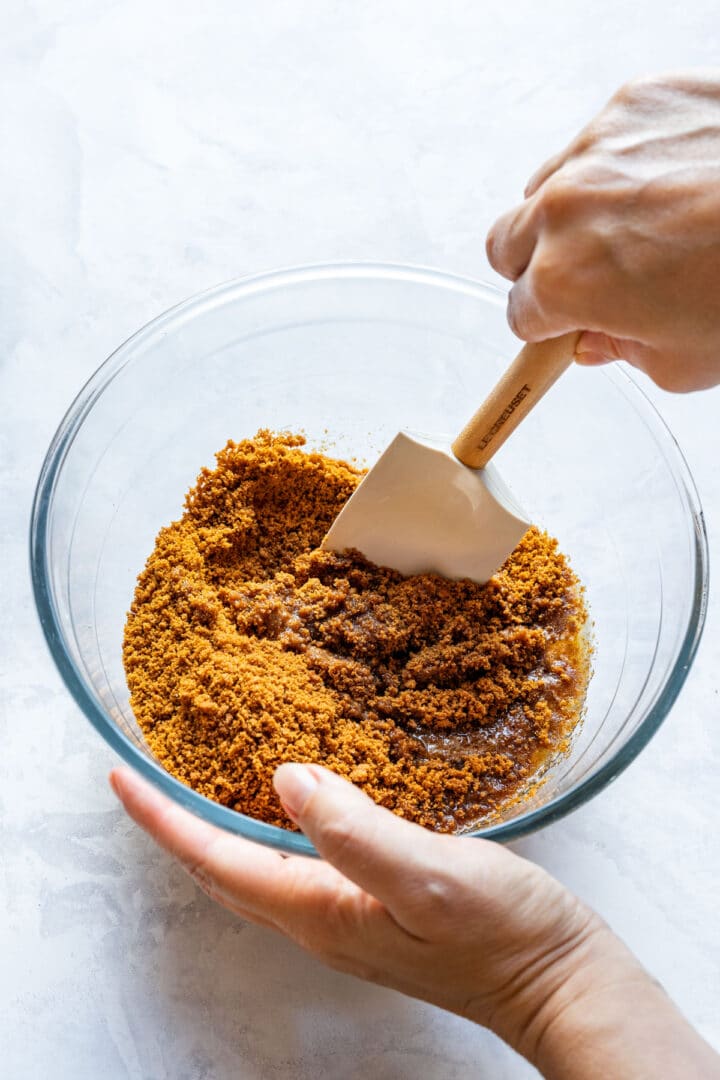 Mixing crushed Biscoff cookies with melted butter for the tart crust.