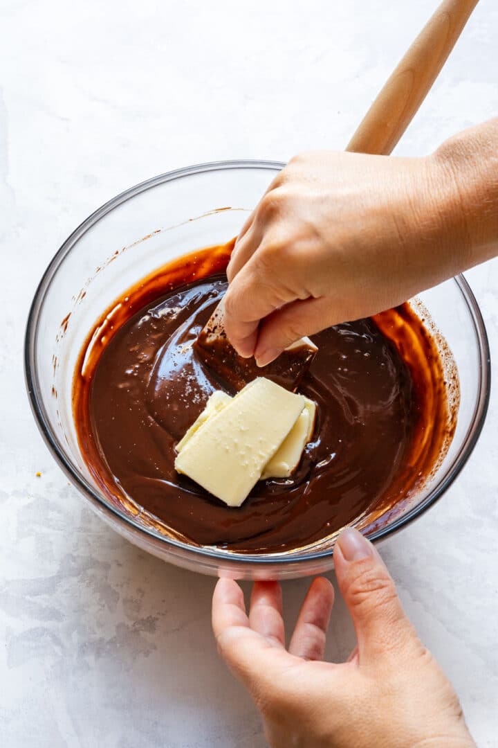 Stirring chocolate ganache with butter until smooth.