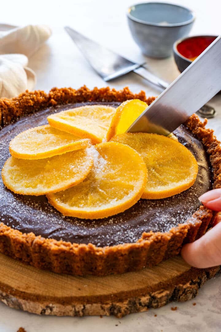 Slicing the tart topped with candied oranges for serving.