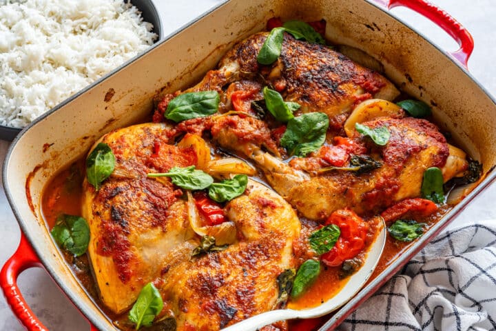 Oven-baked chicken in tomato sauce with spinach, served with rice.