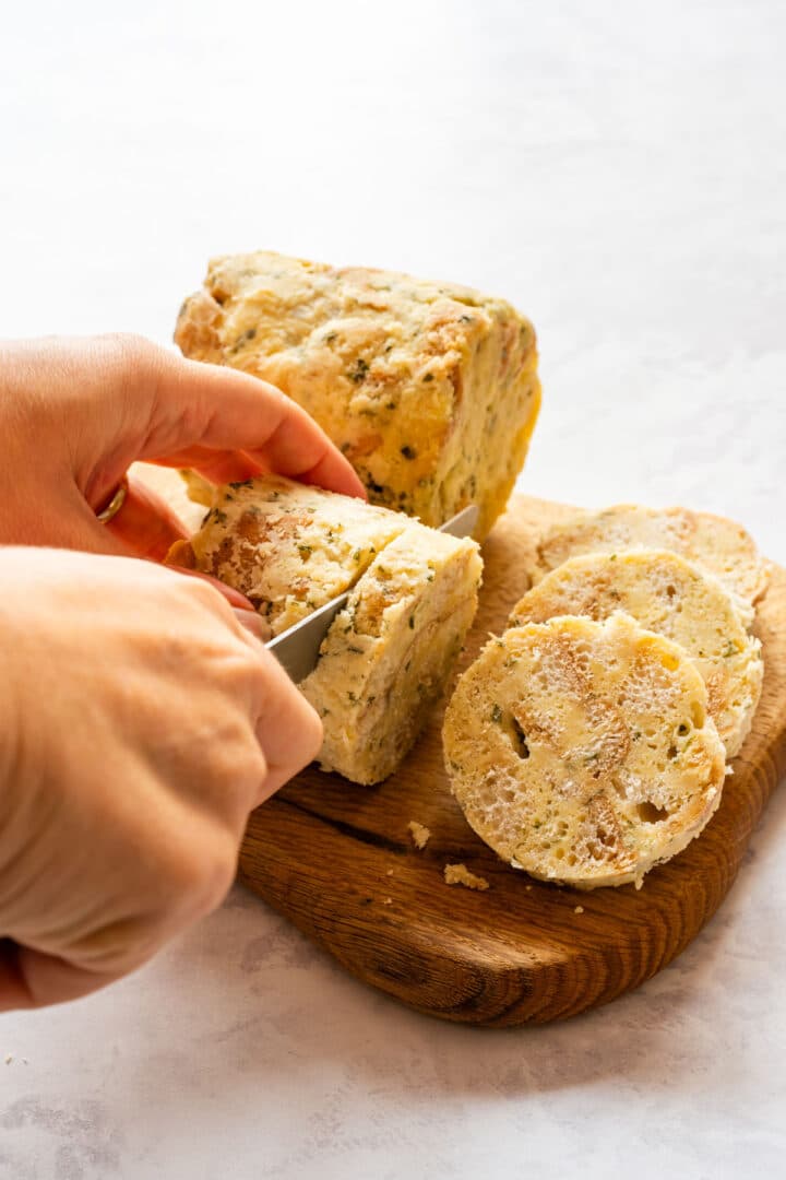 Slicing cooked Carlsbad dumplings to show the soft bread-based interior.