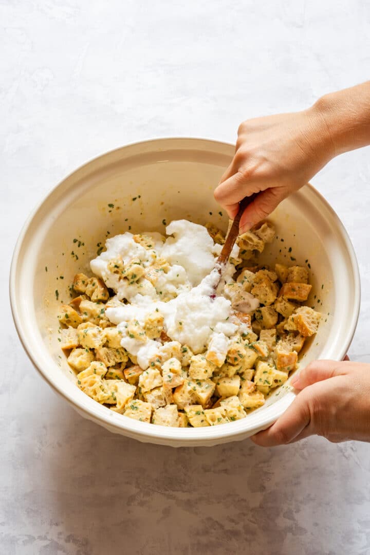 Folding whipped egg whites into bread dumpling mixture in a large bowl.
