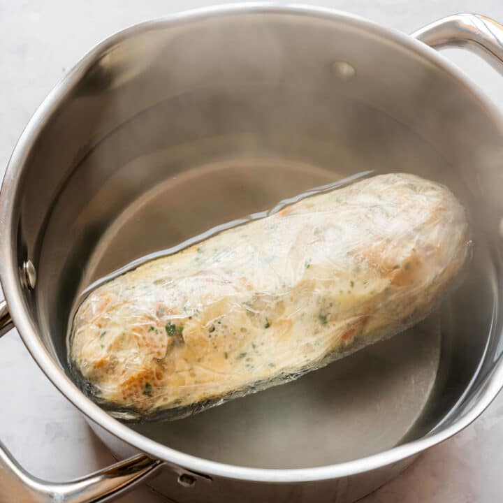 Wrapped bread dumpling cooking in a pot of gently boiling water.