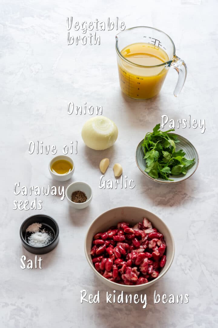 Ingredients for red bean soup including red kidney beans, vegetable broth, onion, garlic, parsley and caraway seeds.